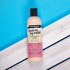 Hands apply Knot On My Watch to damp hair for quick detangling during wash day.