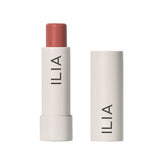 ILIA Balmy Tint Hold Me lip balm close-up showing warm peachy nude color and moisture.