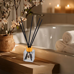 Lily Roy soy candle with diffuser sticks creating warm spa ambience.