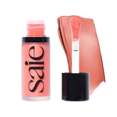 Saie Dew Liquid Blush wand applies poppy glow tint.