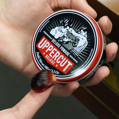Uppercut Deluxe pomade tin close-up highlights glossy finish and premium texture.