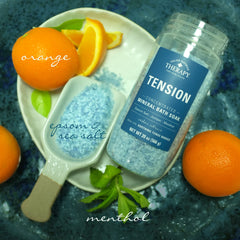 Village Naturals Therapy Tension Bath Soak Epsom salt crystals dispersing in bath water