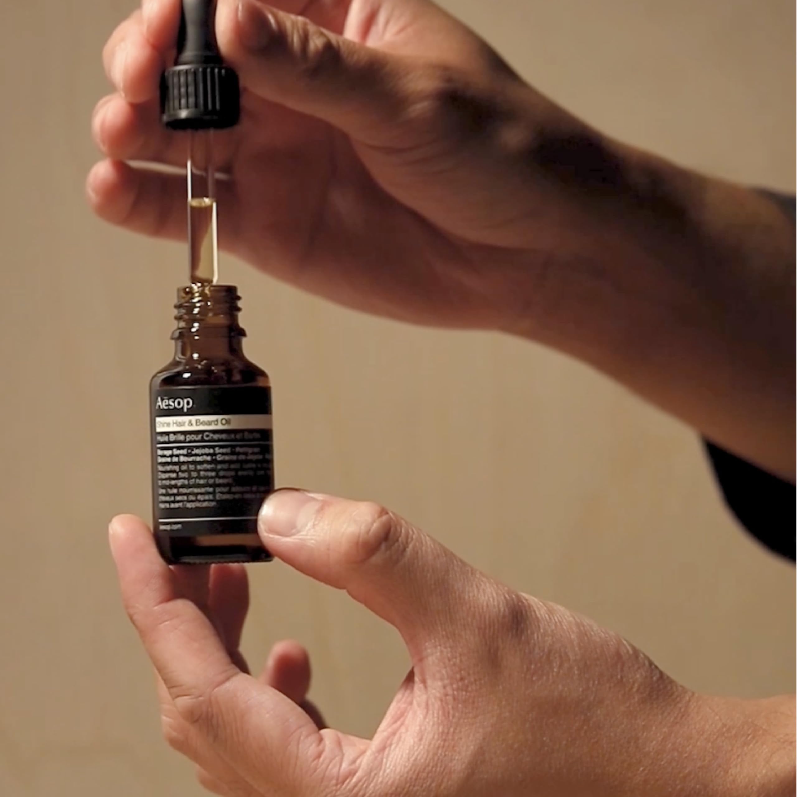 Aesop Shine Hair Oil in hands ready for even distribution.