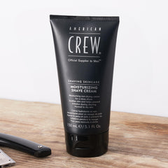 American Crew man applying shave cream for protective barrier and smooth razor glide.