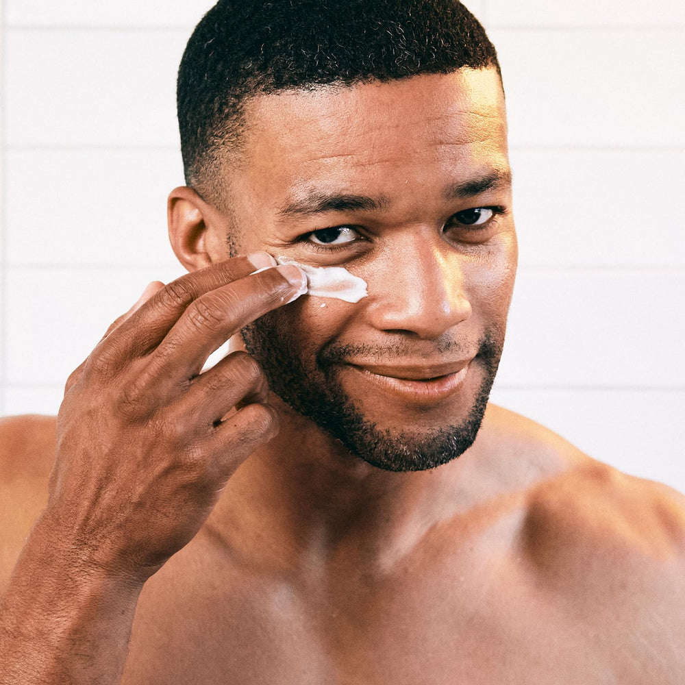 Brickell Men's Restoring Under Eye Cream being applied with fingertips for gentle, fast-absorbing care.