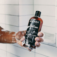 Brickell Men's Revitalizing Hair Conditioner application on hair for smoother, fuller strands.