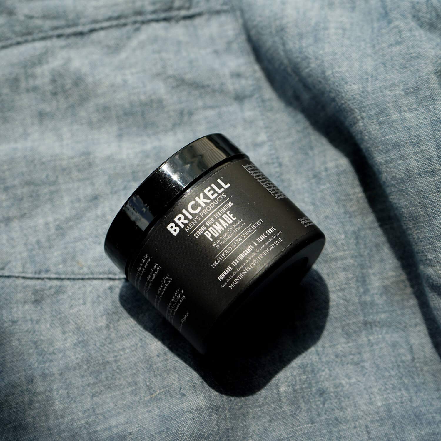 Brickell Strong Hold Pomade hands applying for easy, controllable styling.