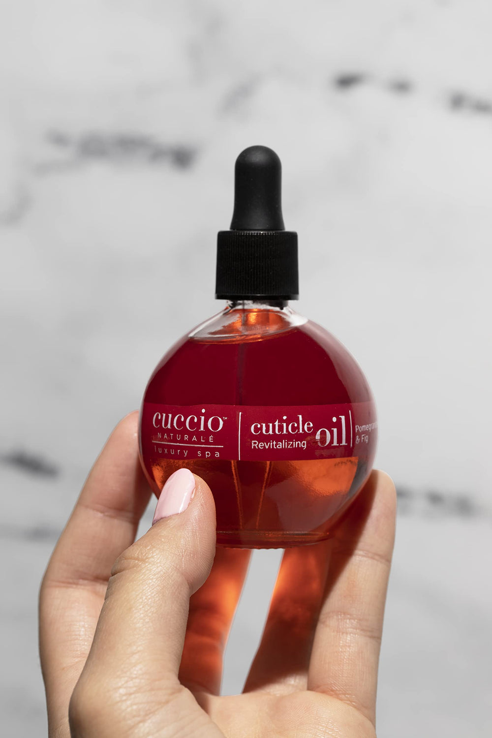 Cuccio Naturale Revitalizing Cuticle Oil being applied to cuticles and nails for care.