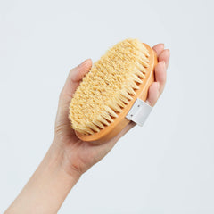 ELEMIS Body Detox Skin Brush in hand demonstrates dry brushing to boost circulation.
