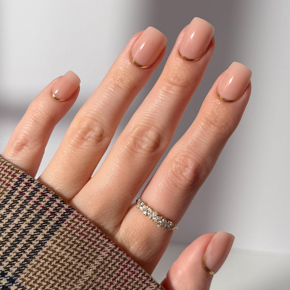 Glamnetic Goal Setter nails on hand with nude base and gold reverse tip for fast, salon-style manicure.