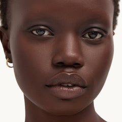 Goop Beauty Cleansing Balm melting from balm to oil shown on skin.