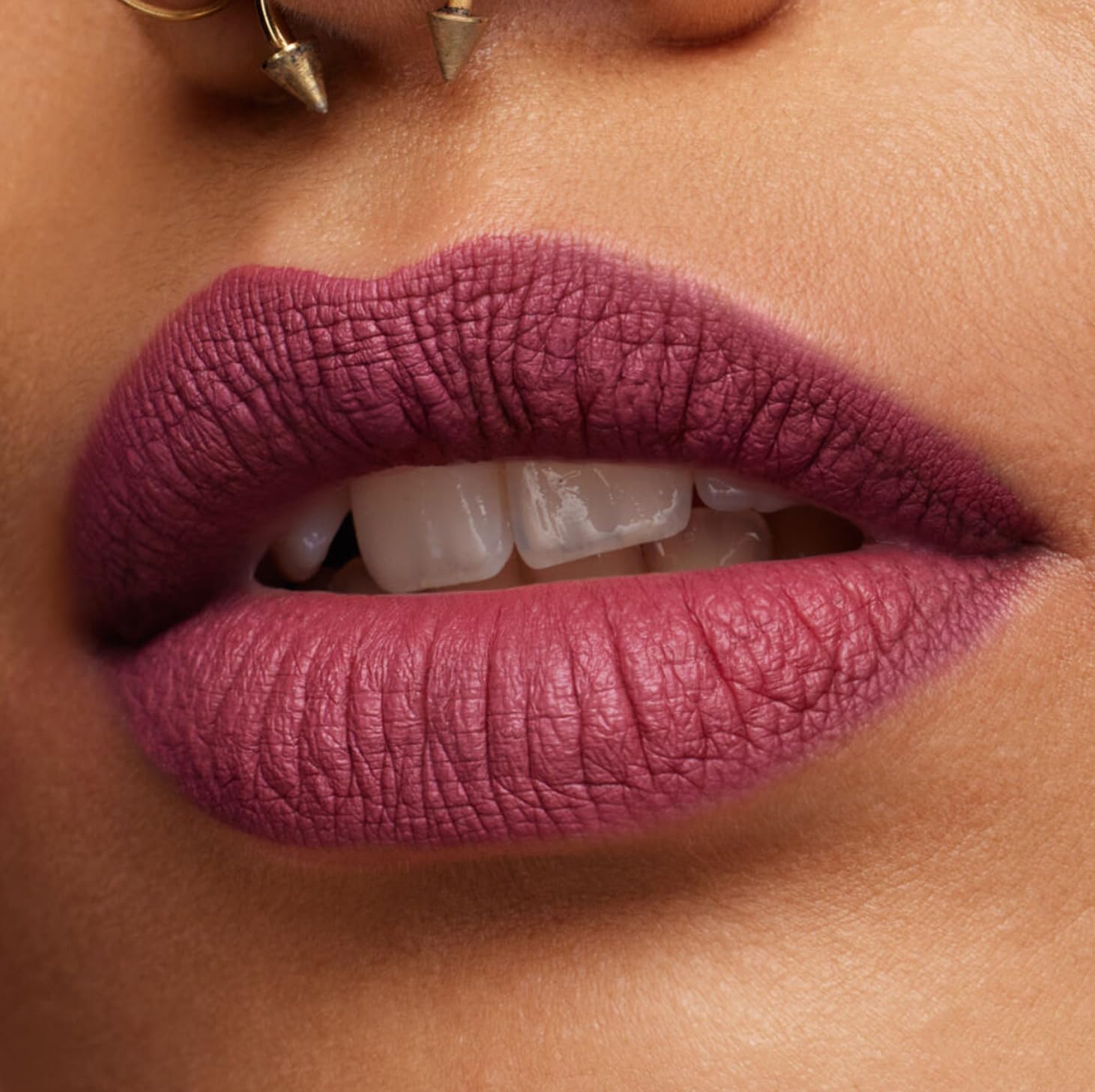 Huda Beauty Trophy Wife rose wood lip swatch on skin emphasizes true tone under varied lighting.