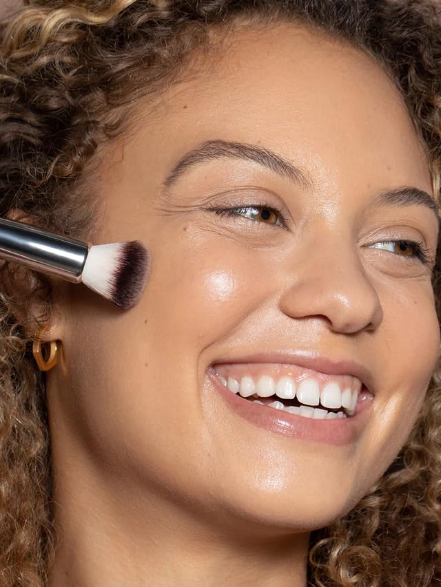 ILIA Complexion Brush in use on the face to apply and buff products evenly.