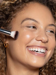 ILIA Complexion Brush in use on the face to apply and buff products evenly.