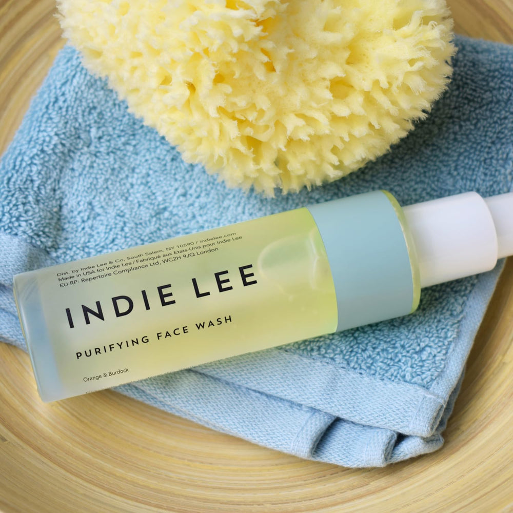 Indie Lee Purifying Face Wash in hand for daily cleansing.