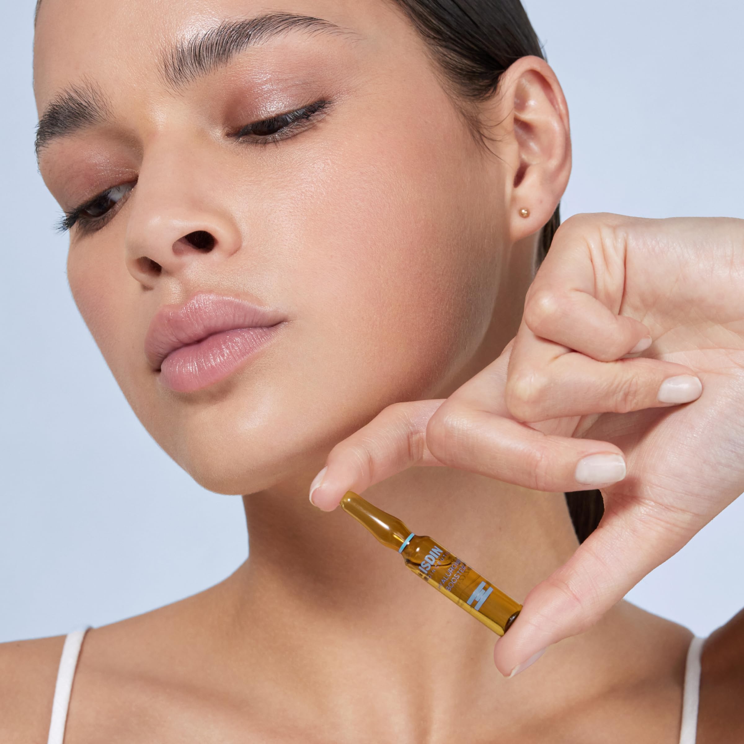 ISDIN Isdinceutics serum glass ampoule closeup showing precise application.