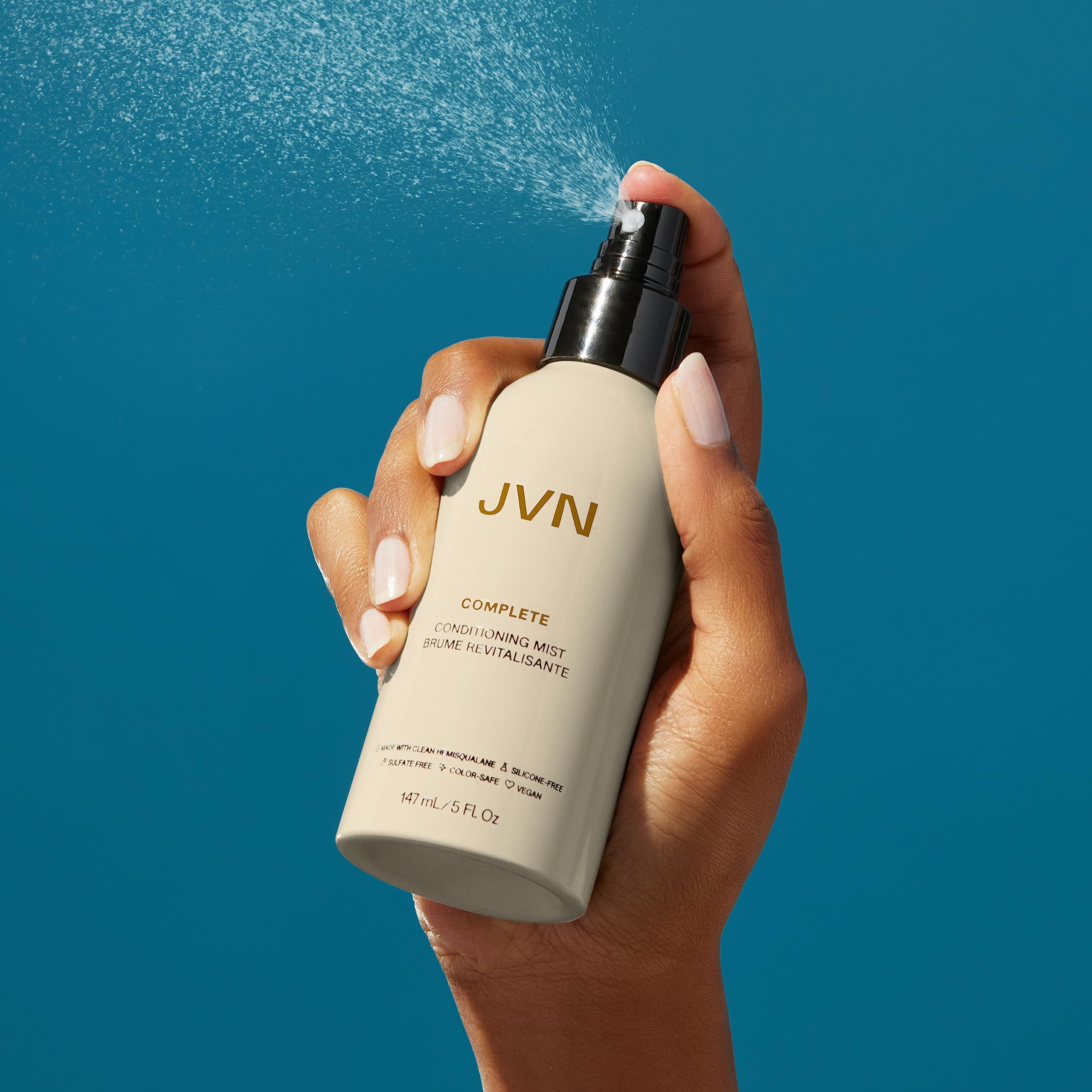 Travel-size JVN leave-in mist beside compact pouch for on-the-go care