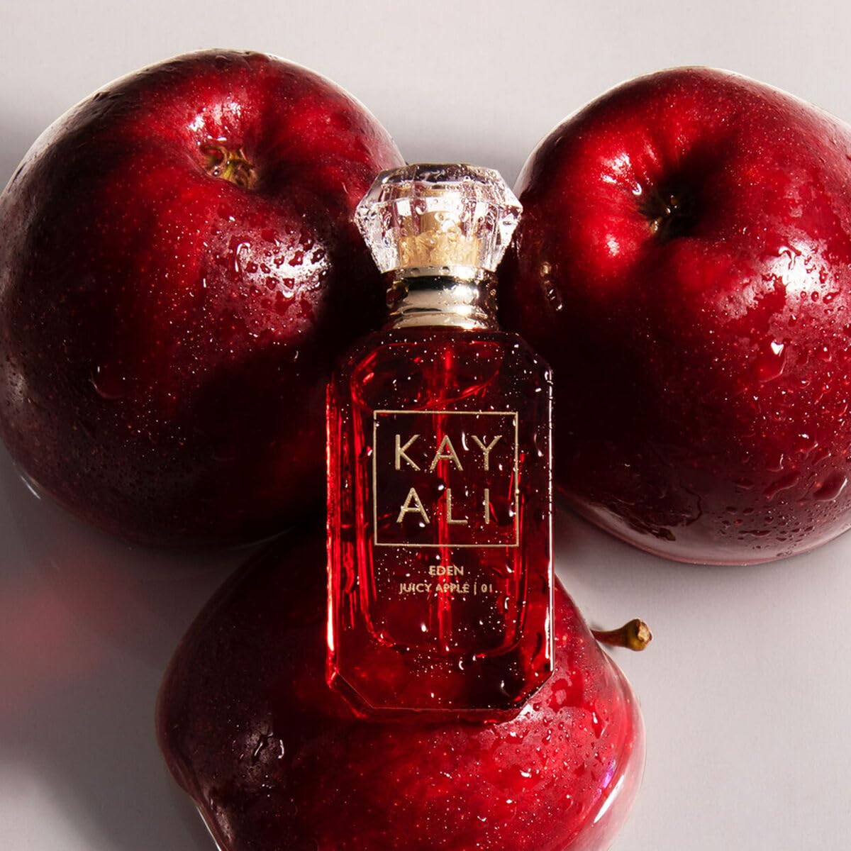 Kayali Eden Juicy Apple bottle on wooden background suggests premium travel-friendly scent.