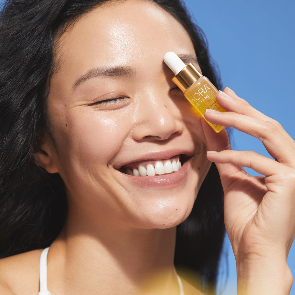 KORA Organics Noni Radiant Eye Oil Roller application closeup showing lightweight, non-greasy texture.
