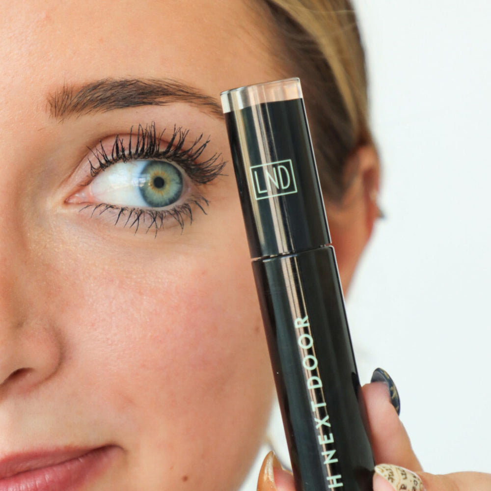 Lash Next Door mascara wand during application demonstrates lengthening effect.