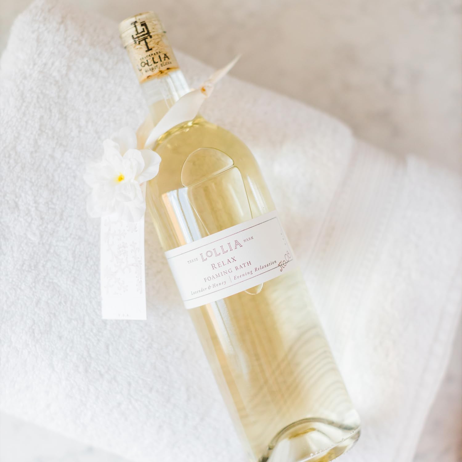 Lollia Relax elegant glass bottle with white flower corsage and satin sash
