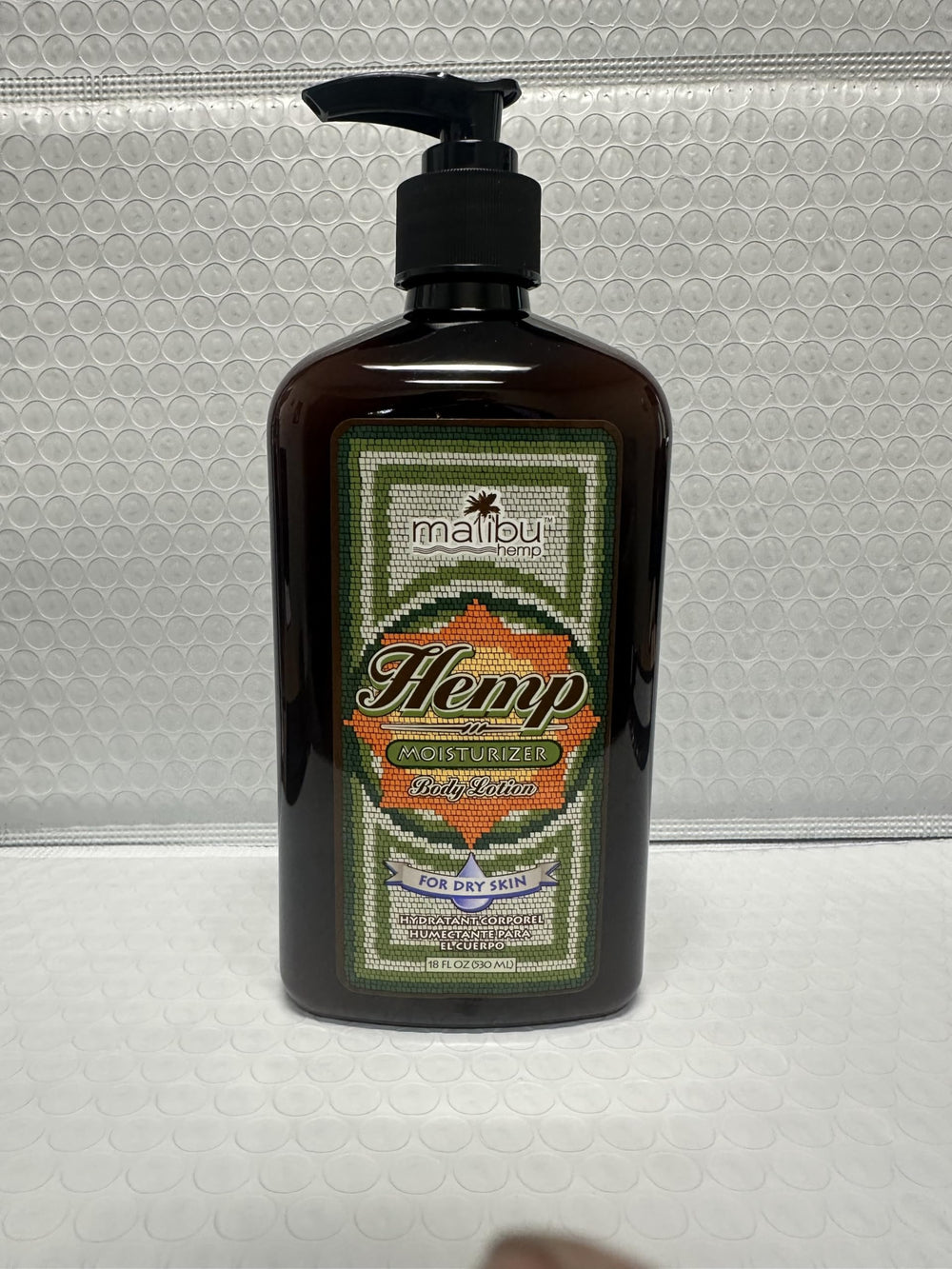 Malibu Tan Body Lotion bottle closeup highlights brand label and ingredients.