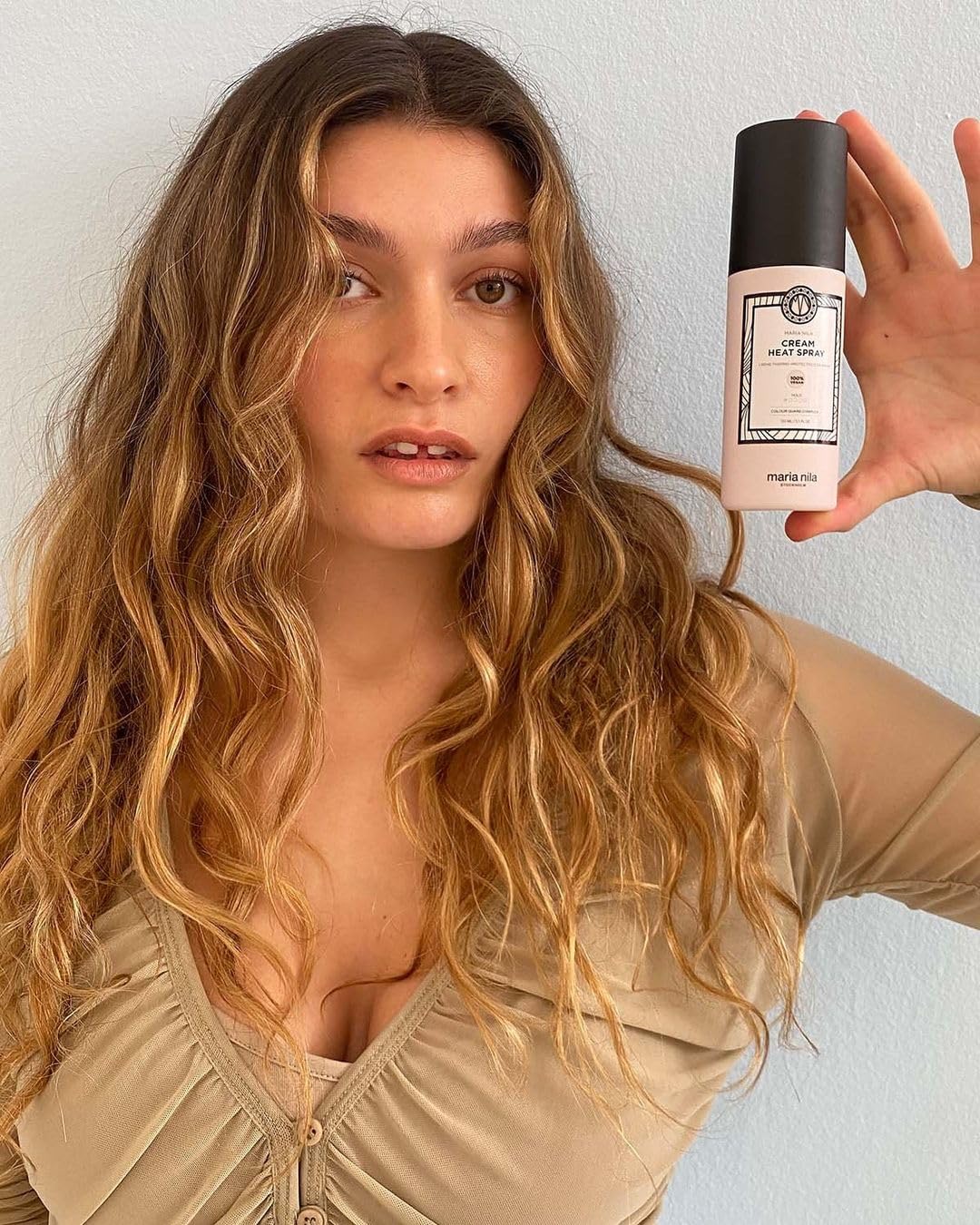Maria Nila Cream Heat Spray hand-application scene suggests even distribution and protection.