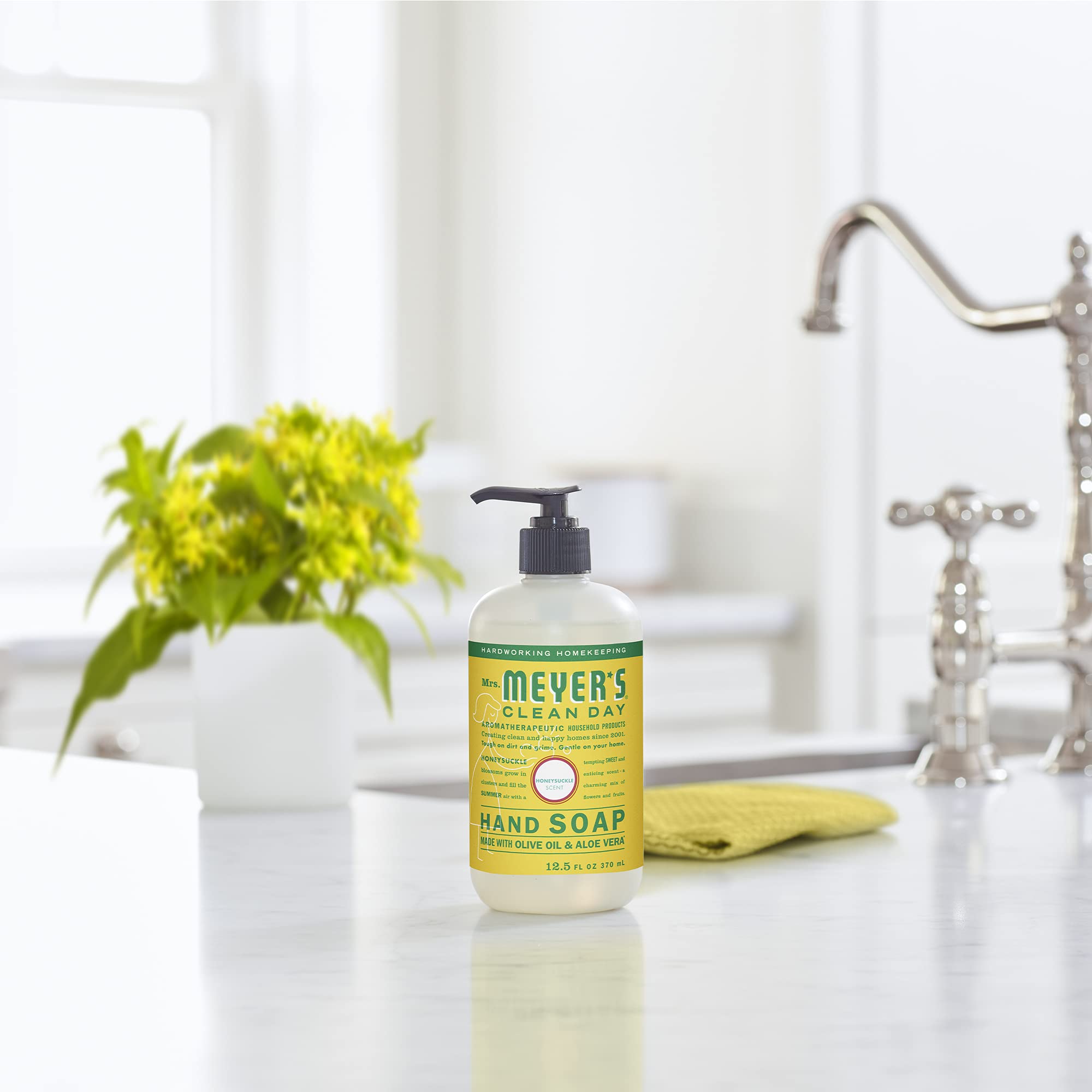 Mrs. Meyer's Clean Day Honeysuckle packaging next to flowers evokes garden-inspired cleanliness.