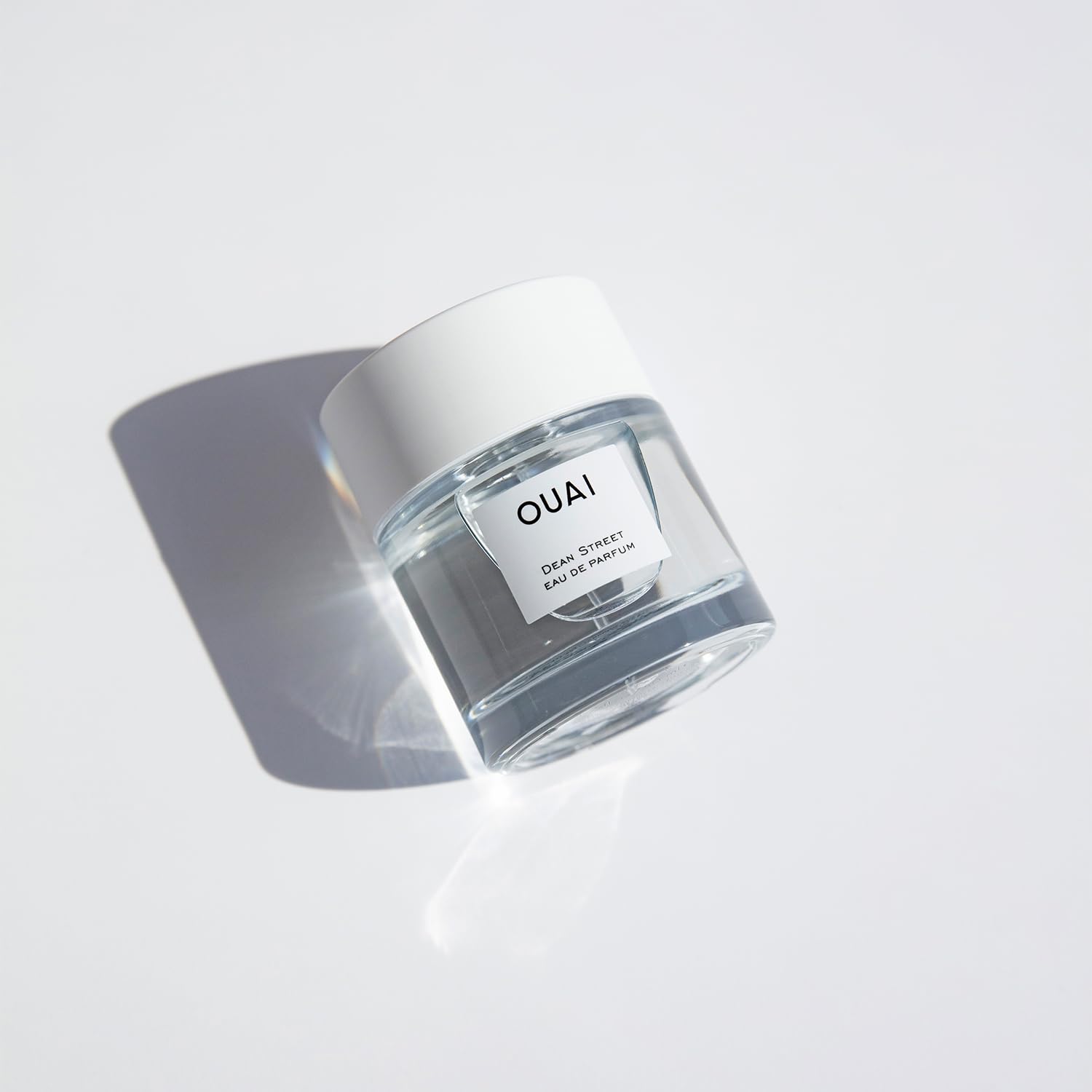 OUAI Dean Street cap and bottle against a neutral background emphasizing citrus-rose balance.