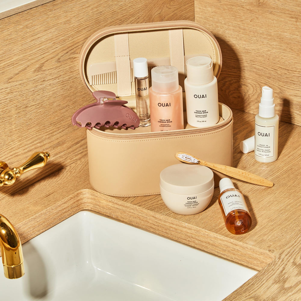 OUAI travel-size conditioner being applied to hair focusing on mid-shaft and ends