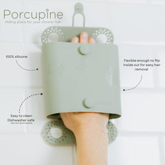 Porcupine shower wall hair catcher with suction cups mounted on wall surface.