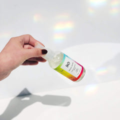 R+Co Mood Swing applying spray to hair shows quick-dry and frizz-control benefits.