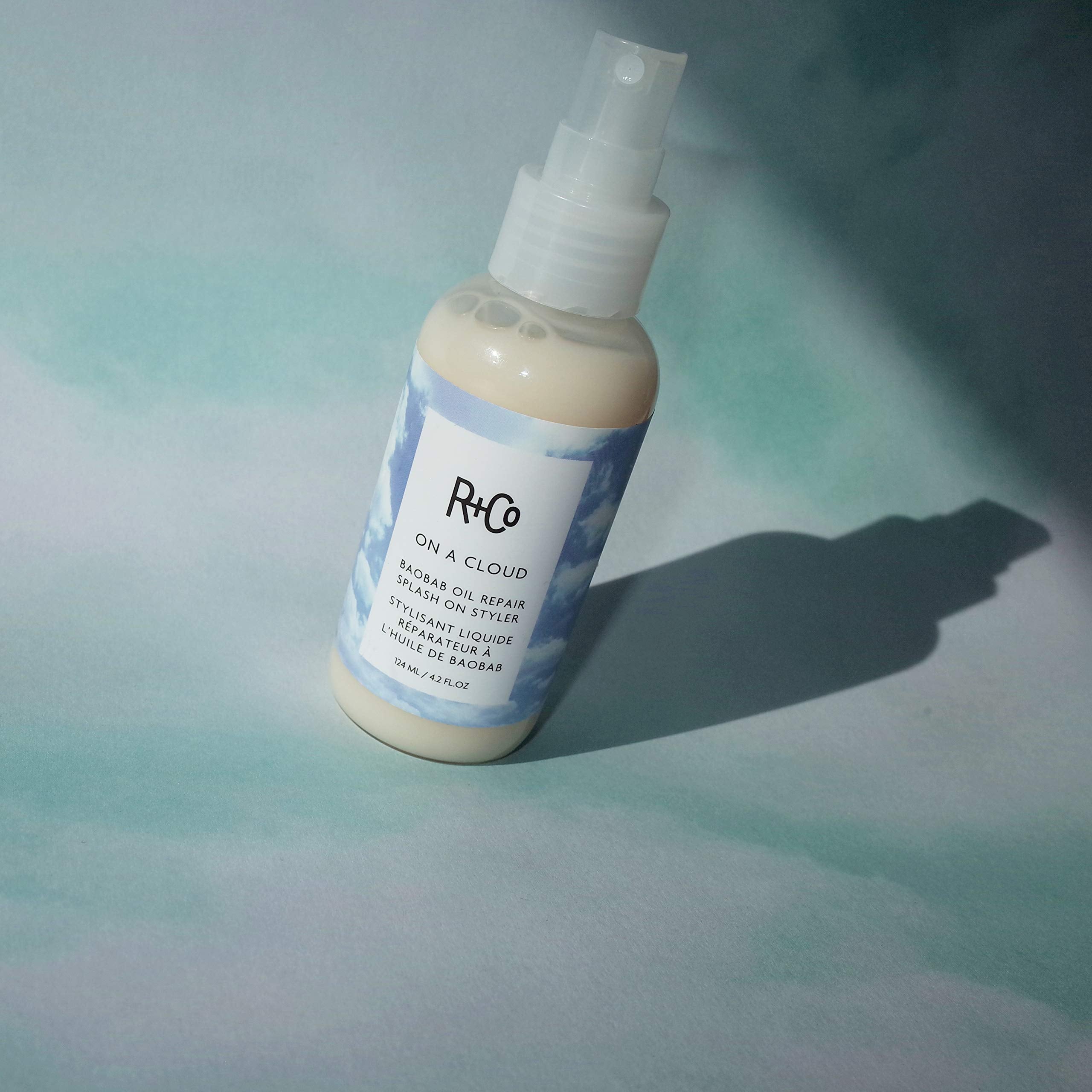 Applying R+Co On A Cloud Baobab Oil Repair Splash to smooth frizz.
