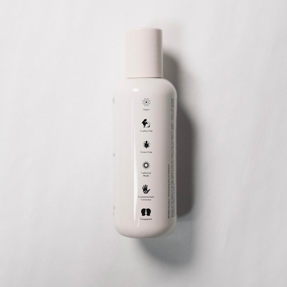REVERIE Natural Balancing Shampoo application at sink illustrates easy distribution for scalp cleansing.