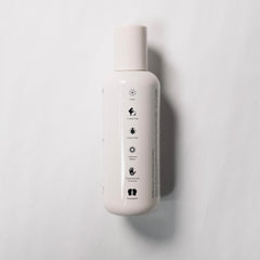 REVERIE Natural Balancing Shampoo application at sink illustrates easy distribution for scalp cleansing.