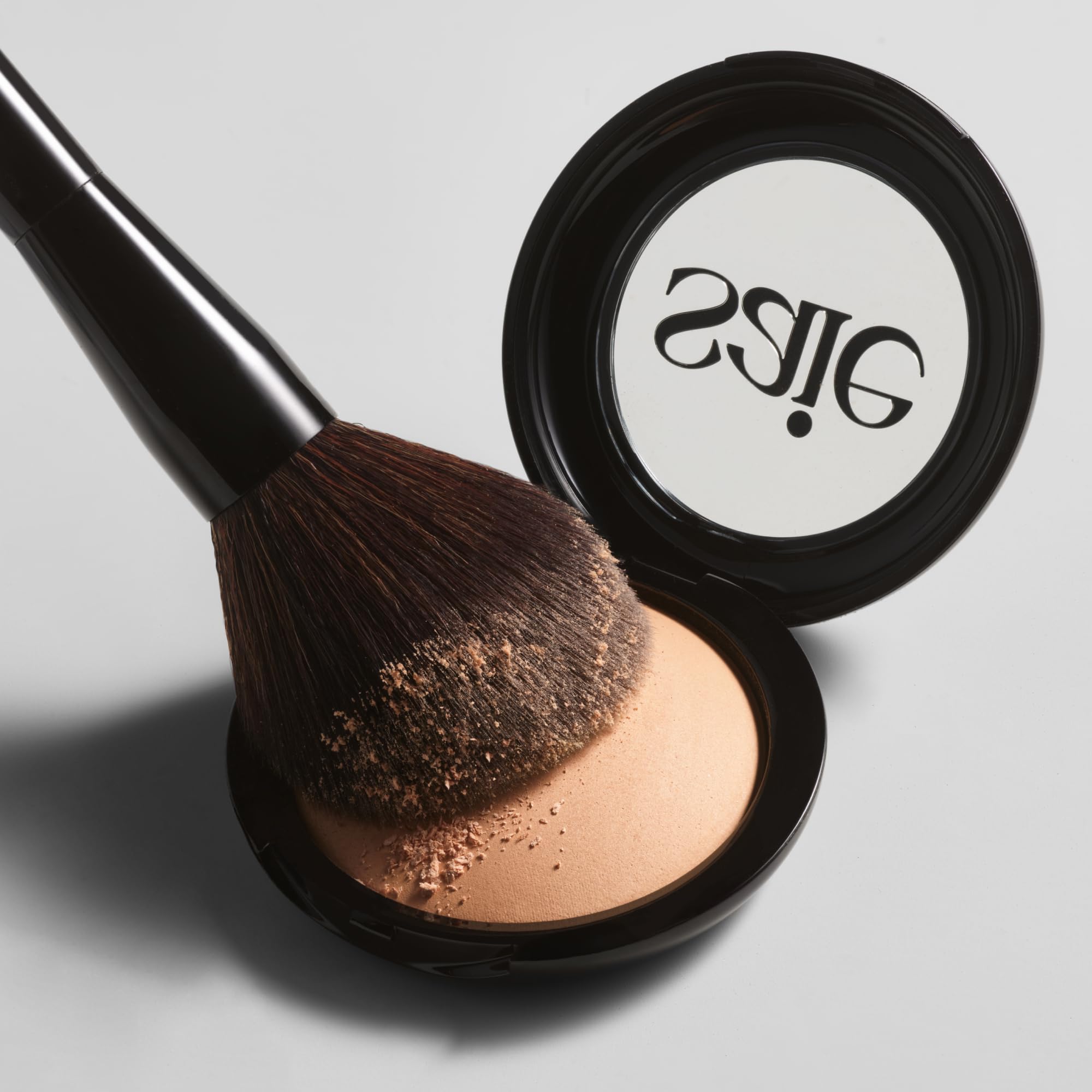 Saie brush beside Slip Tint packaging for coordinated powder application