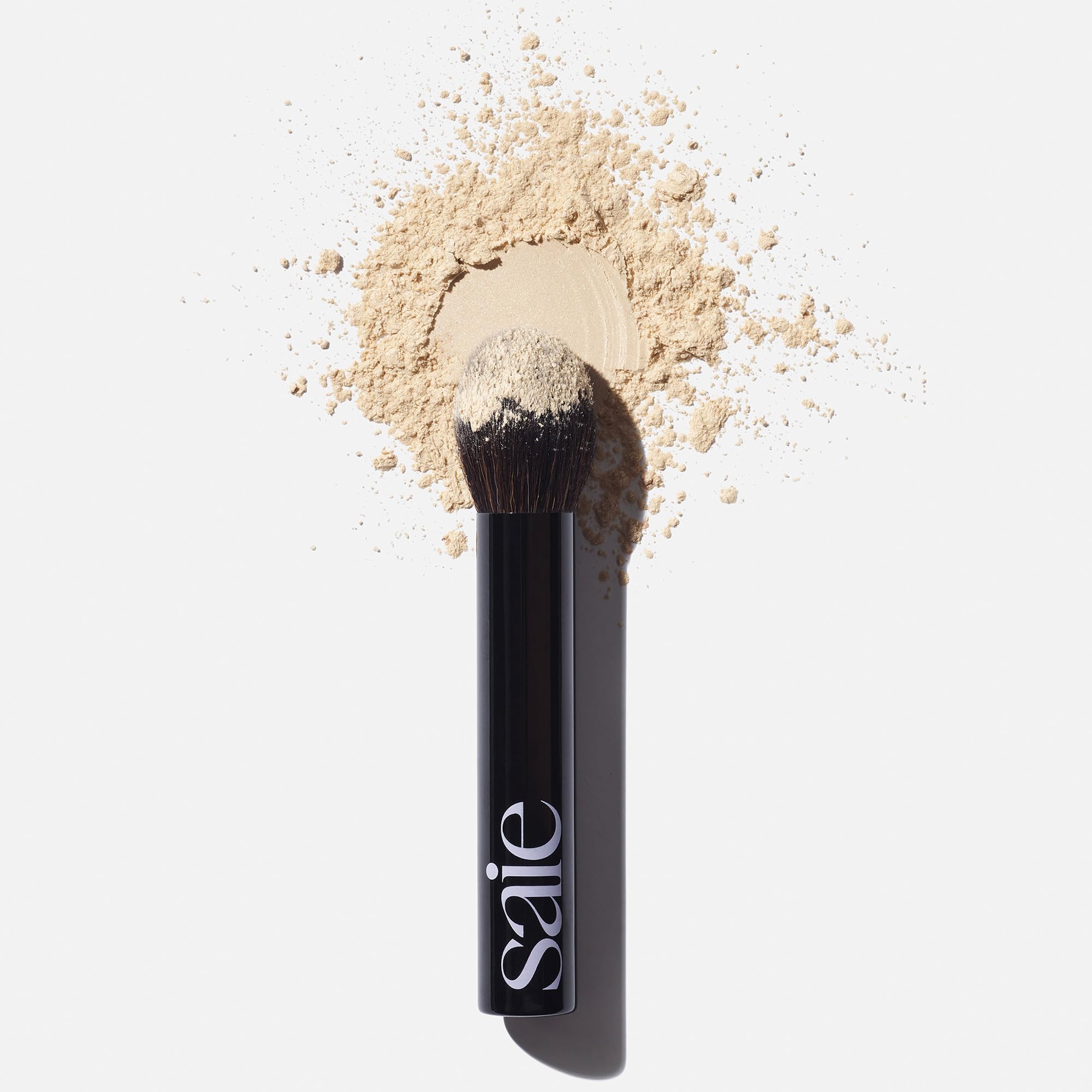 Saie The Fluffy Brush tapered-tip for pinpoint powder placement on high-shine zones.