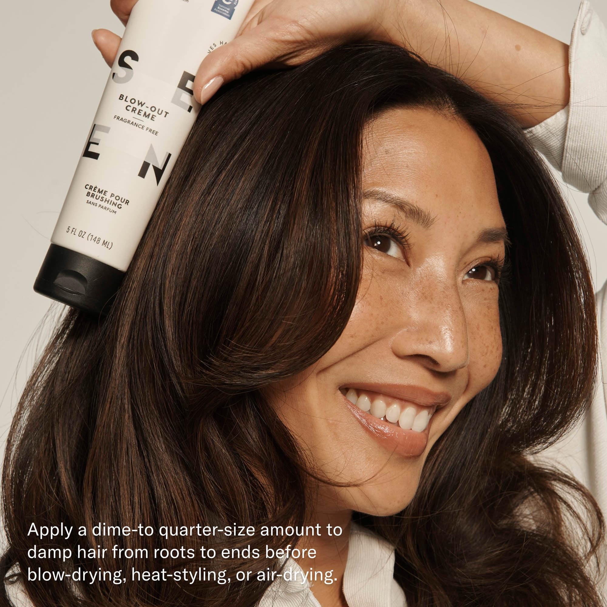 Hand applying SEEN Blow-Out Creme to damp hair for smooth styling