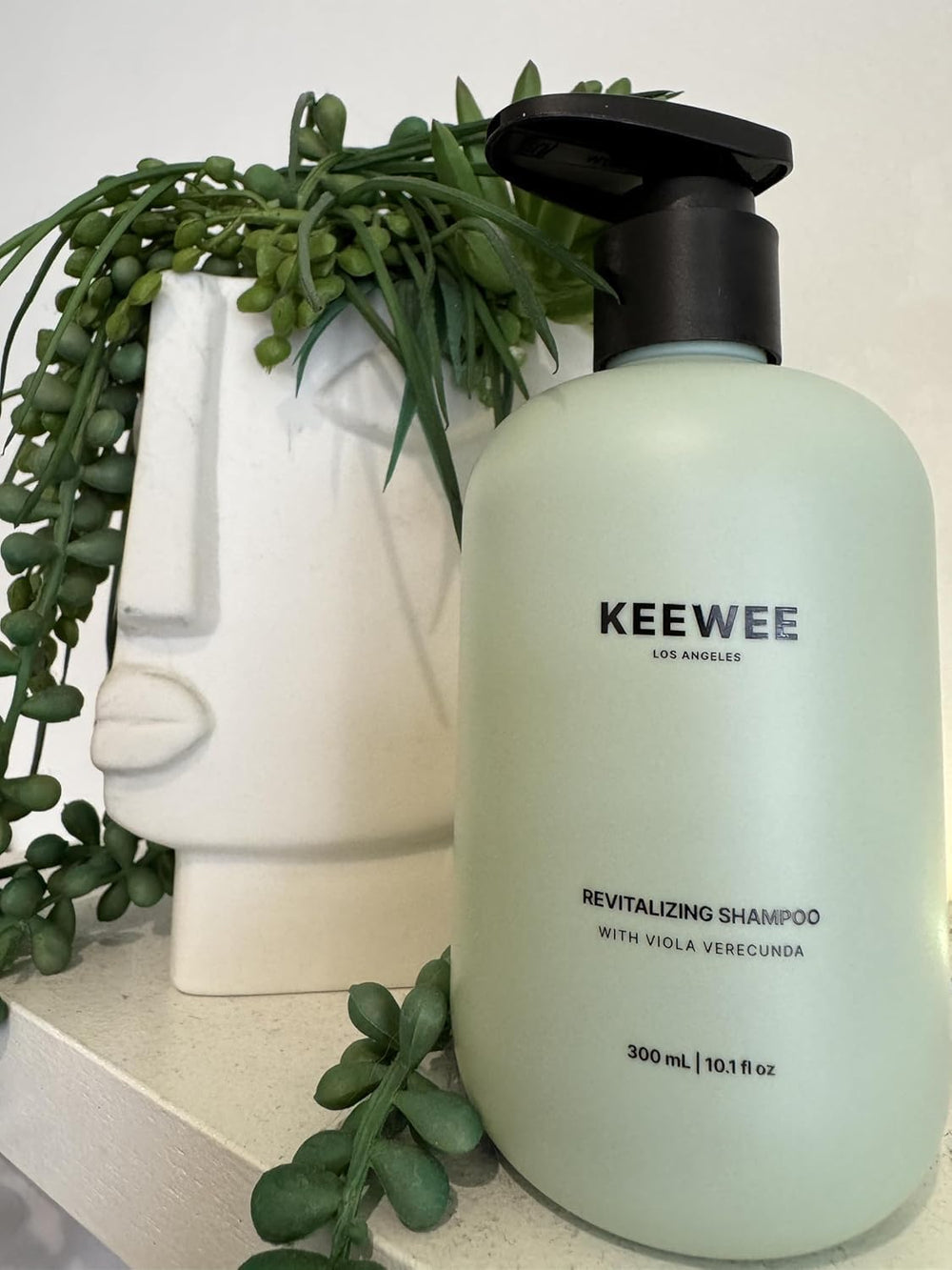 SRILabs KEEWEE bottle beside healthy-looking hair with volume.