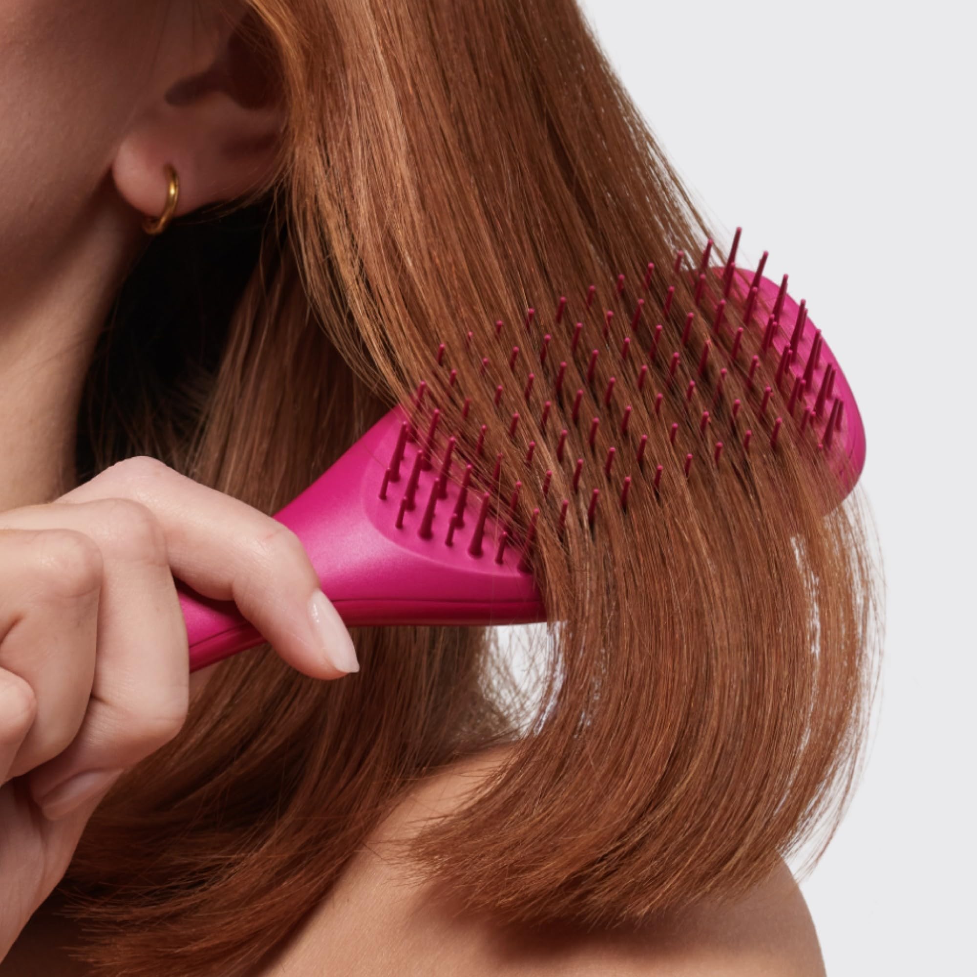 Raspberry-colored Tangle Teezer Ultimate Detangler in a travel kit setup