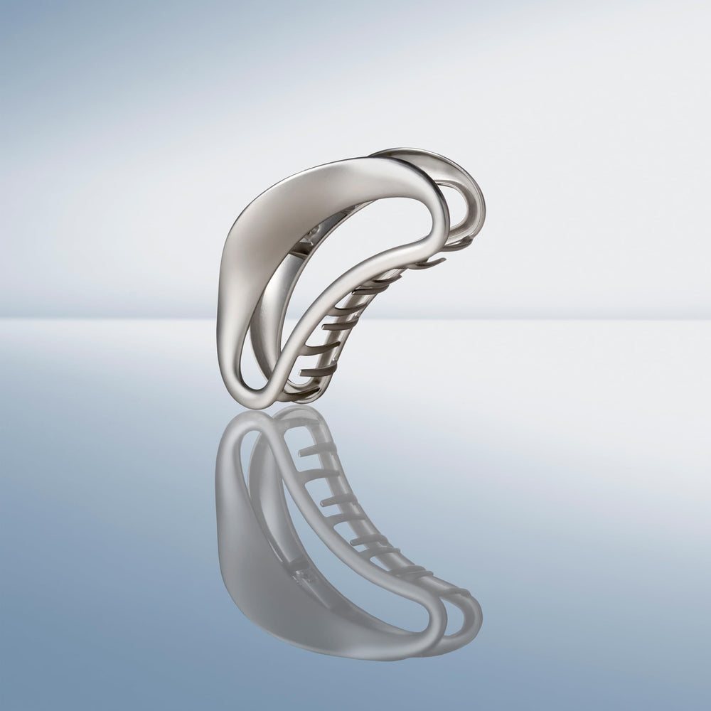 The Hair Edit Sculpted Silver Claw Clip on dresser suggesting effortless ready-to-go beauty accessory.