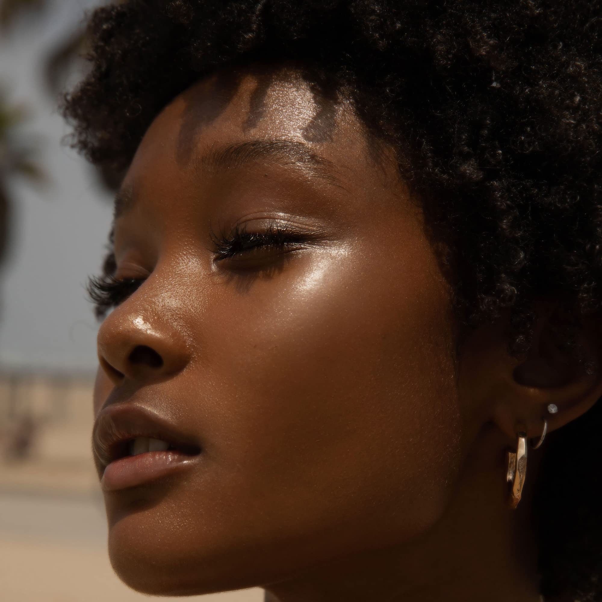 Tower 28 SuperDew balm applied to cheekbone for natural radiance.
