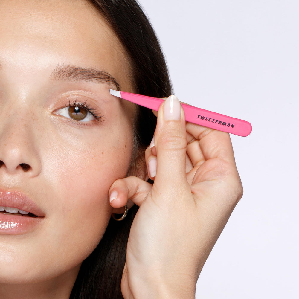 Tweezerman neon pink handle closeup emphasizes vibrant grip and control during tweezing