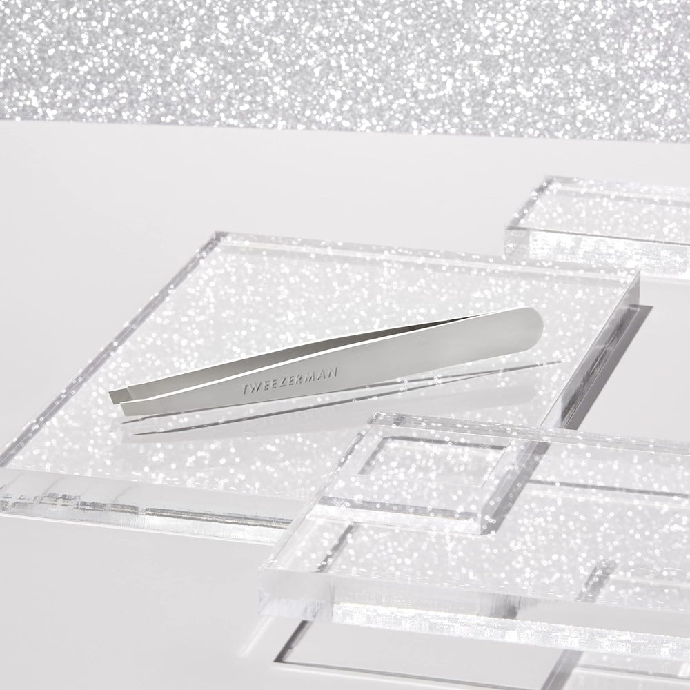 Tweezerman platinum silver tweezer holding fine hair for removal.