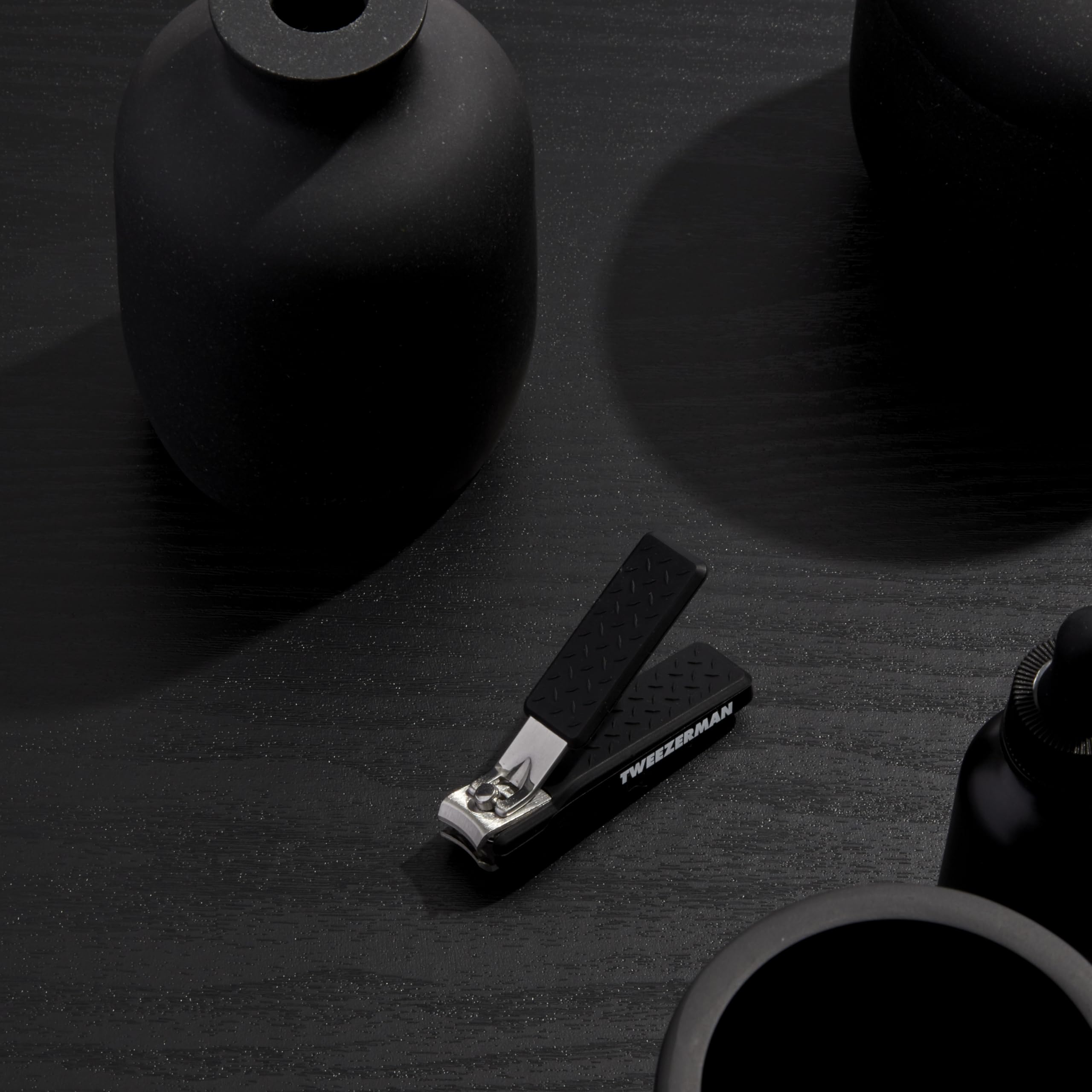 Tweezerman Precision Grip Fingernail Clipper in black shown in-use for clean, precise trimming.