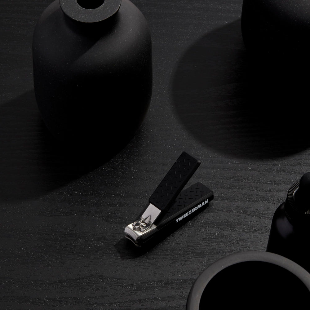 Tweezerman Precision Grip Fingernail Clipper in black shown in-use for clean, precise trimming.
