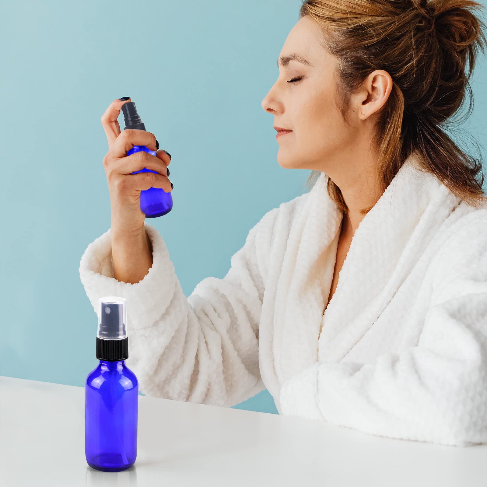 Wedama 4oz mini glass spray bottles blue in-use with skincare or cleaners.